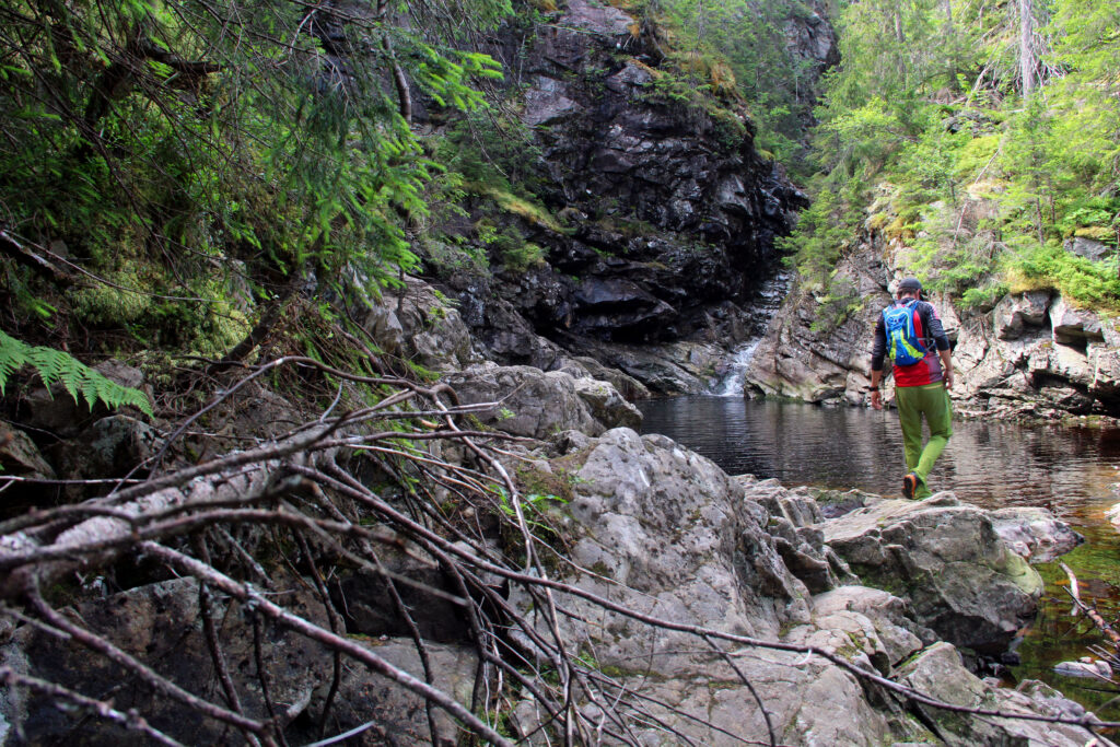 Det er vakkert nede i bunnen av juvet, og med lav vannføring er det mulig å utforske området både oppover og nedover på elvebunnen, her fra nedre fossefall, hvor det også er mulig å bade i kulpen ved fossen.